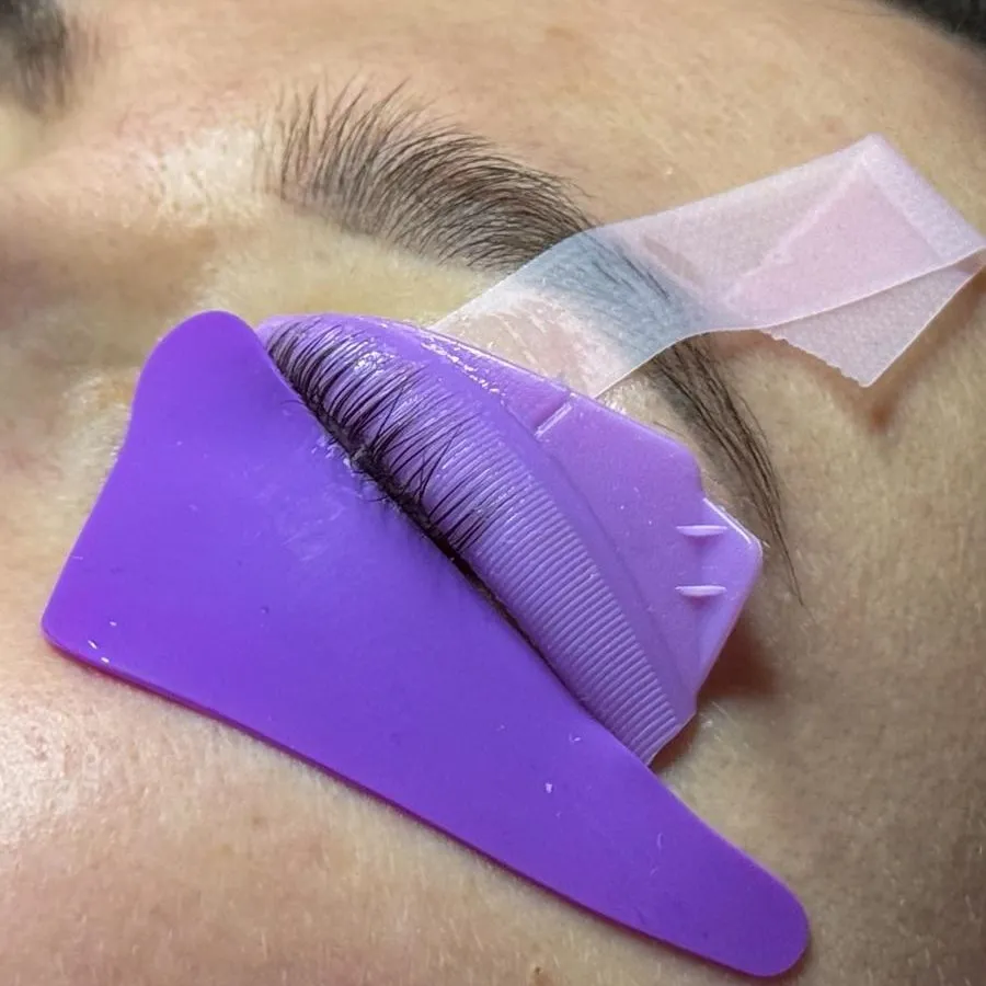 Lashlifting: die Wimpern liegen auf einer violetten Silikonform, die Haut ist mit Tape abgeklebt.