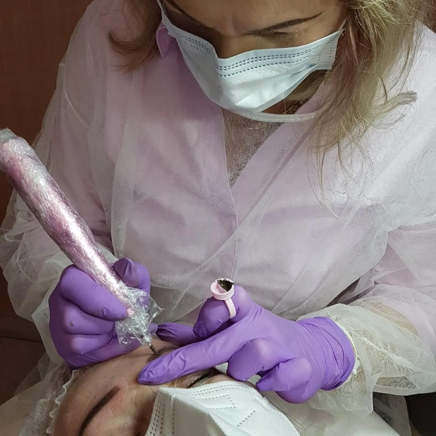 Agata Höfemann pigmentiert die Braue einer Kundin mit dem Pigmentiergerät; am Finger sitzt der Ring mit der Farbe.