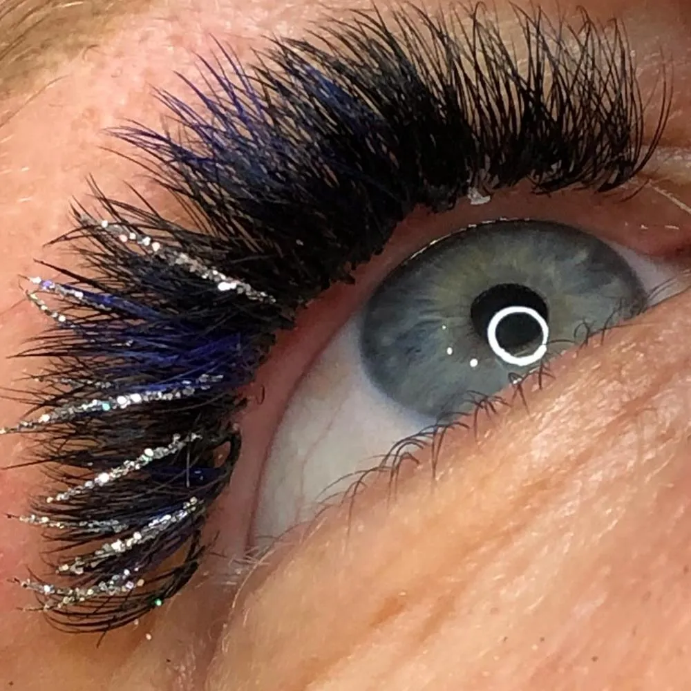 Wimpern mit Farbakzent: einzelne Strähnen in Blau, dazu silberner Glitzer an den Spitzen.